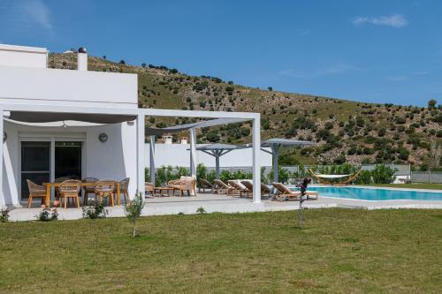 a white house with a pool and a hill at Villa Miniera in Linopótis