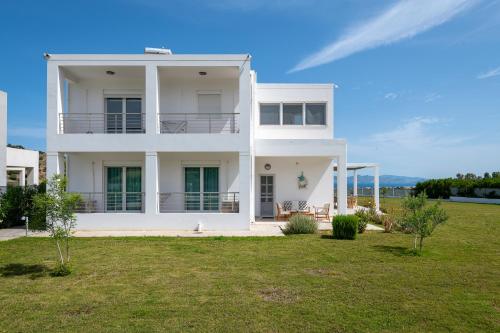 a white house with a lawn in front of it at Villa Miniera in Linopótis