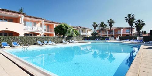 une grande piscine bleue devant un immeuble dans l'établissement L Olivier de la Palmeraie, à Grimaud