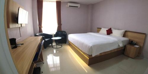 a bedroom with a bed and a desk and a window at Great Cokro Edotel Lampung in Lampung