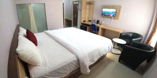 a bedroom with a bed and a desk and a television at Great Cokro Edotel Lampung in Lampung