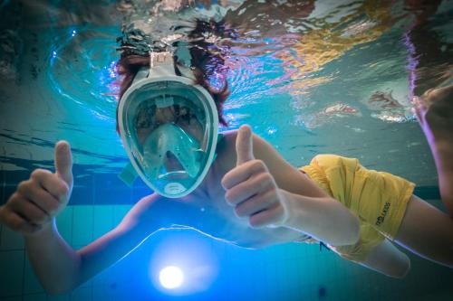 a person in a swimming pool with a camera at Trixi Park Zittauer Gebirge - Ferienhäuser, Hotel und Camping in Großschönau