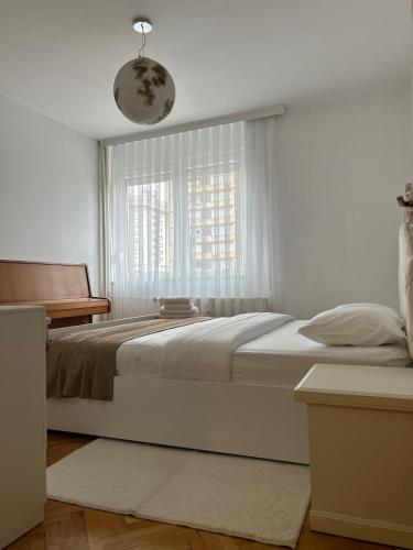 a white bedroom with a large bed and a window at City Center Apartment in Pristina