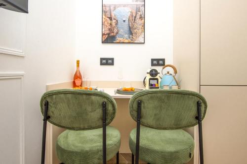 - une cuisine avec deux chaises vertes et une table dans l'établissement SUITE DELUXE - MONACO - Vue Jardin, à Beausoleil