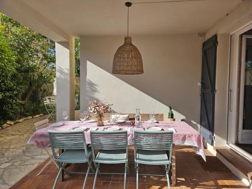 une table à manger avec des chaises et une lampe pendant dans l'établissement Jolie villa avec piscine proche du centre historique, à Arles