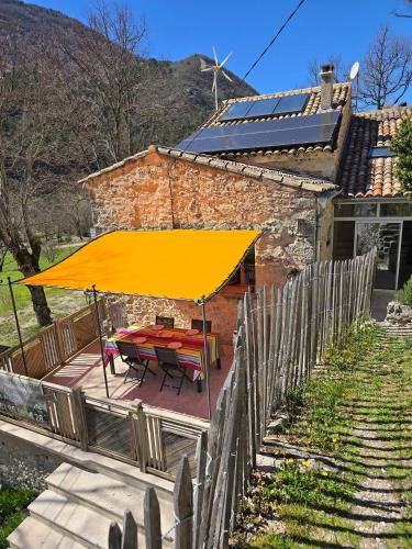 a picnic table with a yellow umbrella in front of a house at Gîte La Magnanerie in Reilhanette