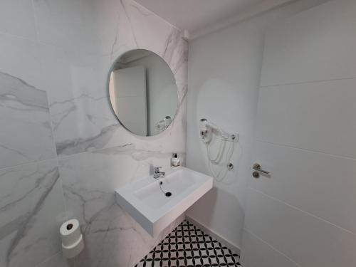 a white bathroom with a sink and a mirror at Apartamentos Alisios con terraza y piscina in Corralejo