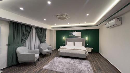 a bedroom with green walls and a bed and two chairs at 1 BHK Sleek Suite Apt in Bahria Heights 1 in Rawalpindi