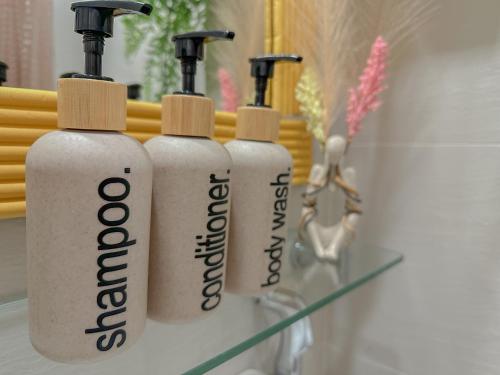 three white bottles sitting on a shelf in front of a mirror at The Sandscape Suite in Manila