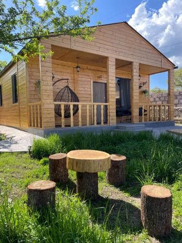 a log cabin with a table and three tree stumps at Eco House in Odzun