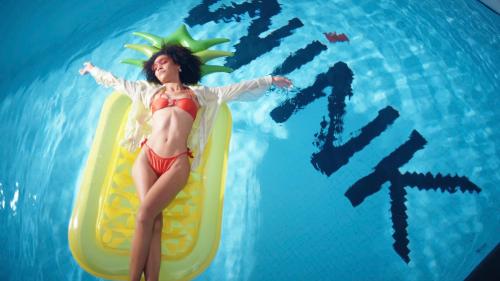 uma mulher de maiô em pé em uma prancha de remo na água em Wink Icon Hotel Danang Riverside - Luxury Suites - 24hrs Stay & Rooftop Pool Bar em Da Nang