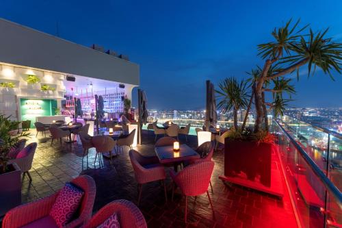 a restaurant with tables and chairs on a rooftop at Wink Icon Hotel Danang Riverside - 24hrs Stay & Rooftop Pool Bar in Da Nang
