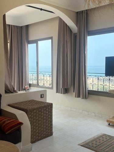 a living room with windows with a view of the ocean at SurfAppart Morocco in Tamraght Ouzdar