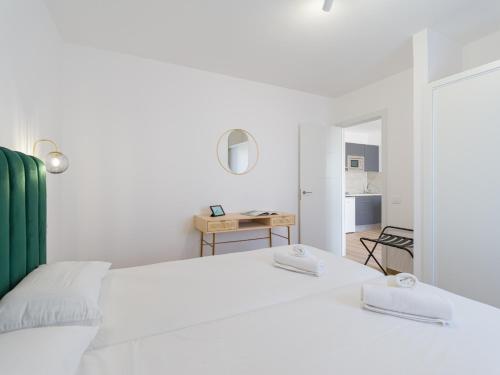 a white bedroom with a bed and a mirror at Alisios Easy Stay in Corralejo