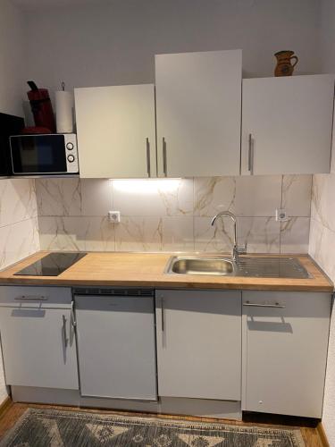 a kitchen with white cabinets and a sink at Modernes Studio in Baden-Baden