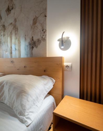 a bedroom with a bed with a wooden headboard and a table at Bujtina Harusha in Theth