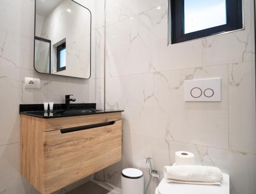 a white bathroom with a sink and a mirror at Bujtina Harusha in Theth