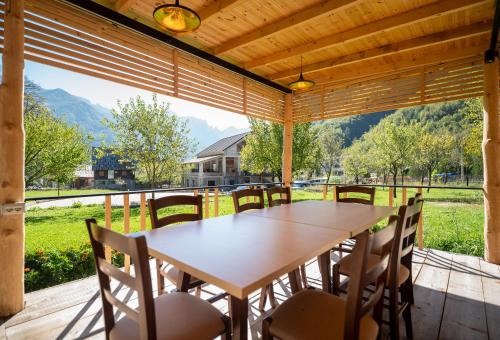 a wooden table and chairs on a porch with a large window at Bujtina Harusha in Theth