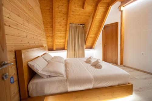 a bedroom with a white bed with wooden ceilings at Bujtina Harusha in Theth