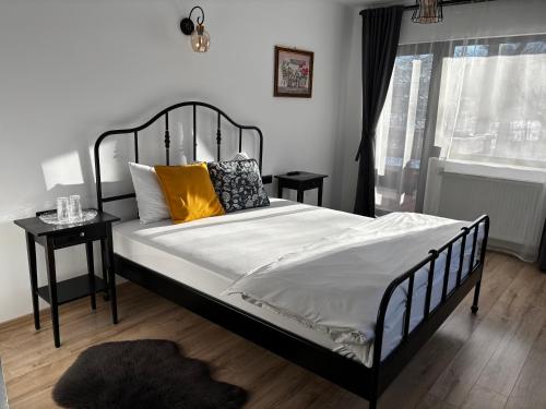 a bedroom with a bed with white sheets and yellow pillows at Frapin House in Braşov