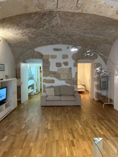 a living room with a couch and a stone wall at Ibiscus apartment in Cagliari