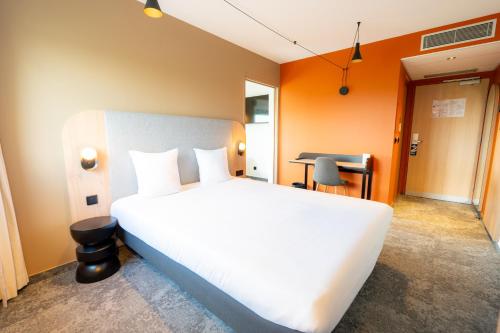 une chambre avec un grand lit blanc et un bureau dans l'établissement Hôtel Akena Reims Bezannes, à Reims