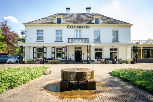 a large white building with a fountain in front of it at Landgoed Hotel & Restaurant Carelshaven in Delden