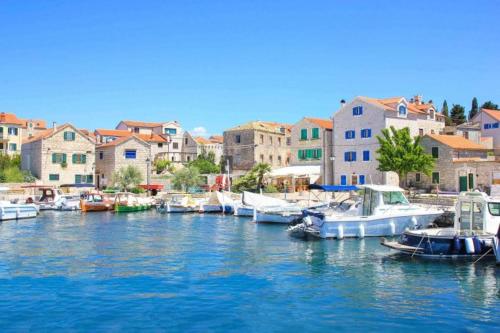 a group of boats docked in a harbor with buildings at Little Beachouse Prvic Island in Prvić Šepurine