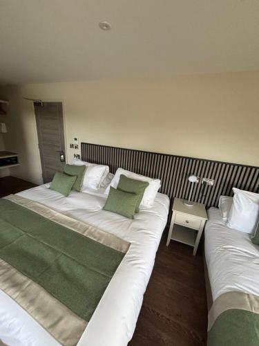 two beds with green pillows in a room at Forest Hills Golf Club in Coleford