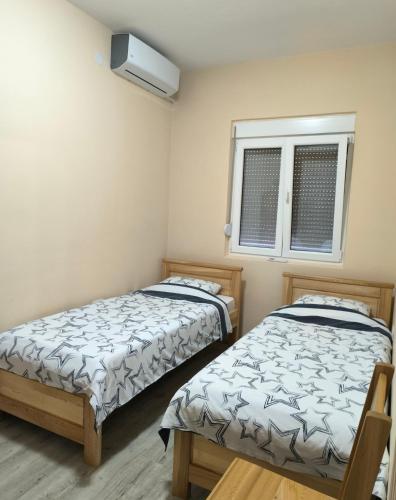 two beds in a small room with a window at Liprosh in Virpazar