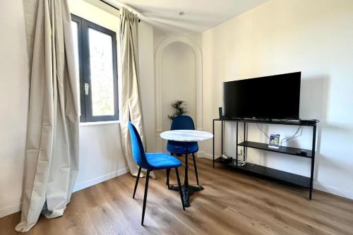 ナンシーにあるNancy Pépinière Appartement rénové et équipéのテーブルと椅子とテレビのあるリビングルーム