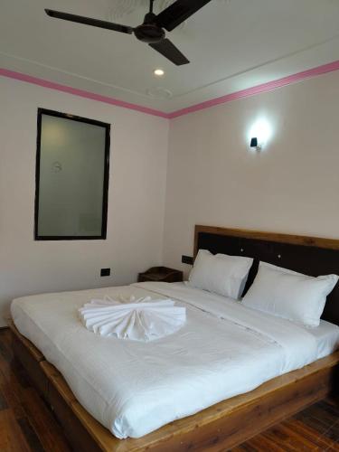 a bedroom with a large white bed with a ceiling at Two Flower Guest House in Leh