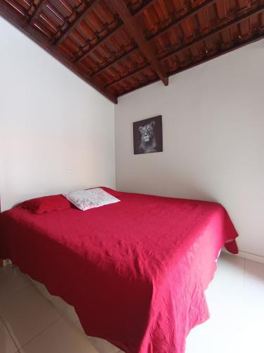 a bedroom with a red bed in a white wall at Quarto Sol Nascente in Tianguá