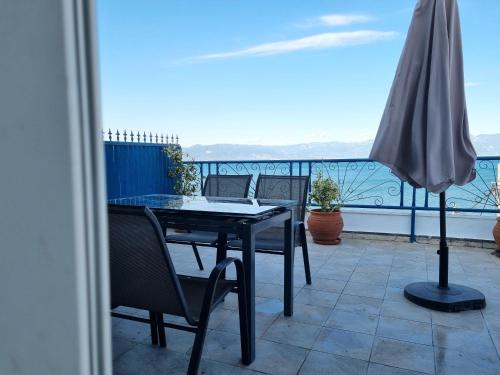 a table and chairs on a balcony with an umbrella at Alkyone in Petalidhion