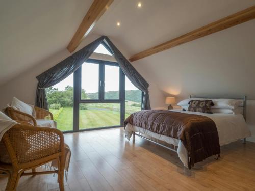 a bedroom with a large bed and a large window at Ty Hen Farm Dairy Penbryn in Tresaith