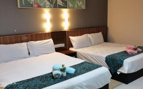 two beds in a hotel room with towels on them at YUYU B2 Honeymoon WiFi Genting highland in Genting Highlands