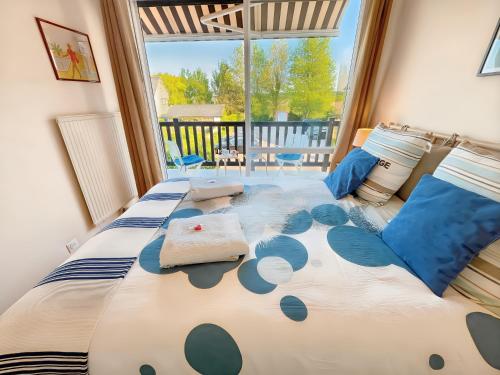 une chambre avec un grand lit avec des oreillers bleus dans l'établissement Blonville sur Mer, 2 minute walk to beach, 2 parking spaces and balcony, à Blonville-sur-Mer
