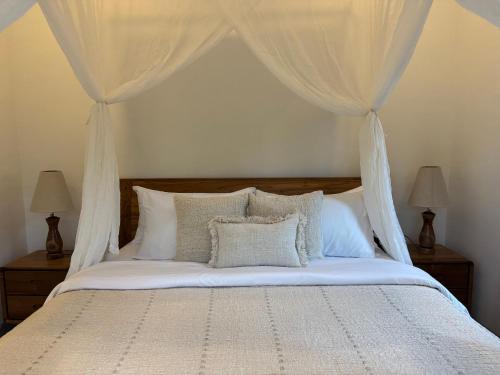 a bedroom with a bed with white curtains and pillows at Gayatri in Ubud
