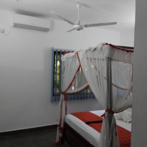a bedroom with a bed with a ceiling fan at Maasai Koroga Hotel & Apartments in Mombasa