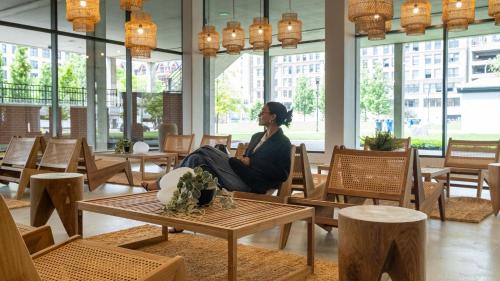 a woman sitting on a chair in a room with tables at Dayton Vitality Hotel - Downtown in Dayton