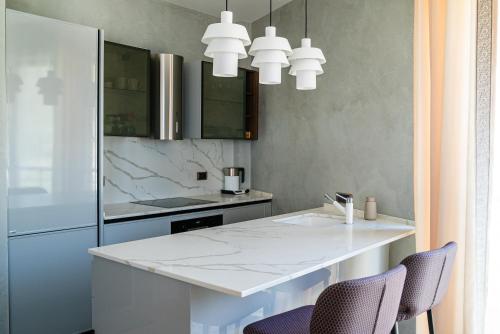 cocina con encimera blanca y 2 sillas en The Royal Summer & Spa, en Bečići