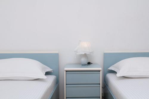 two beds with white pillows and a table with a lamp at Apartments Villa Flamingo in Makarska