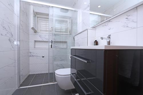 a white bathroom with a toilet and a shower at Apartments Villa Flamingo in Makarska