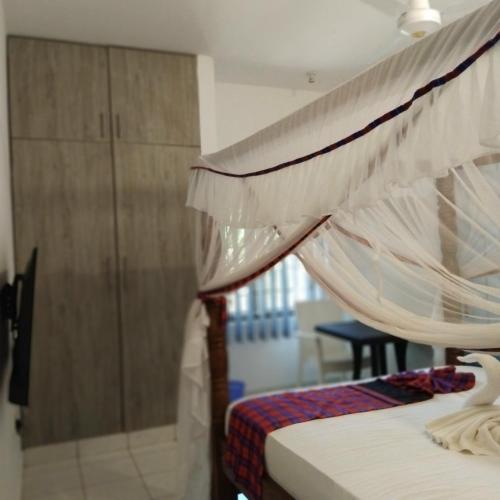 a bedroom with a bed with a canopy at Maasai Koroga Hotel & Apartments in Mombasa