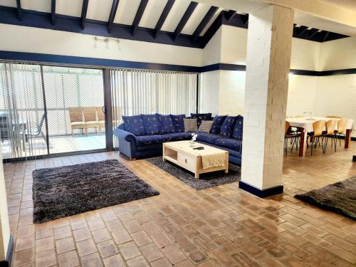 Una sala de estar con un sofá azul y una mesa. en Mandurah Family Resort Bunkhouse, en Mandurah