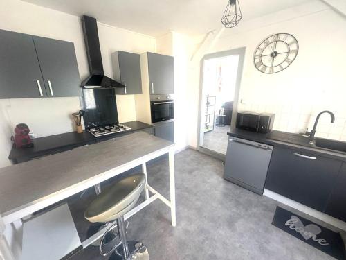 une cuisine avec un comptoir et une horloge au mur dans l'établissement Grand appartement centre-ville, à Belfort