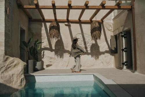 a person standing next to a swimming pool at Manili Boutique Suites & Villas in Archanes