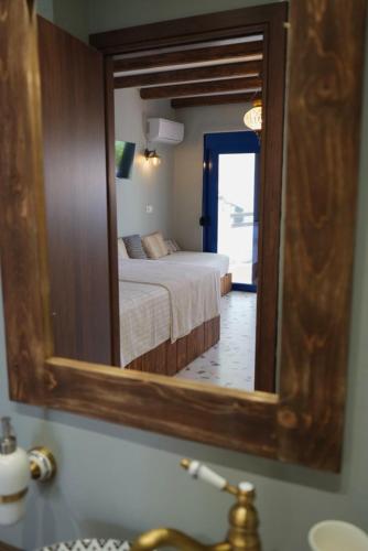 a mirror in a bathroom with a bed in a room at Apágkio Filoxenia in Archangelos