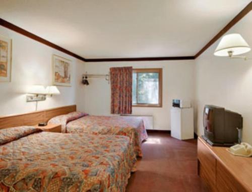 BeckerにあるBecker inn & Suitesのベッド2台、薄型テレビが備わるホテルルームです。