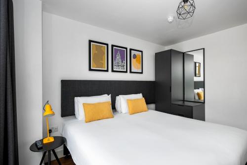 a bedroom with a large white bed with orange pillows at Staycity Aparthotels Liverpool City Centre in Liverpool